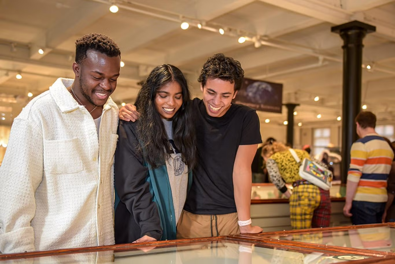 Three young adults look at a museum display case.